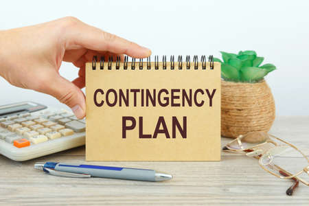 Notepad with text Contingency Plan on a white background, near calculator and office supplies....