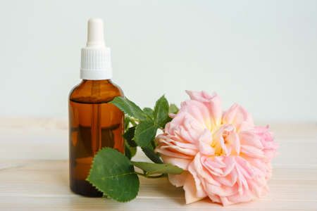 Rose and bottle with aromatic oil or medicine on a white wooden tableの写真素材