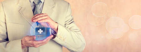 Insurance concept. Health insurance. The insurance agent holds a protective sphere with the image of a first-aid kitの写真素材