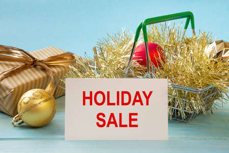 Shopping cart and text HOLIDAY SALE on white paper note list. Shopping list concept.