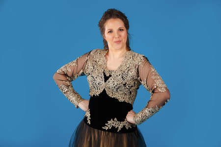 Studio portrait of a woman in a carnival costume of a princess on a blue background.