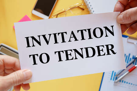 Against the background of the office table - a card with the text Invitation to Tender.の写真素材