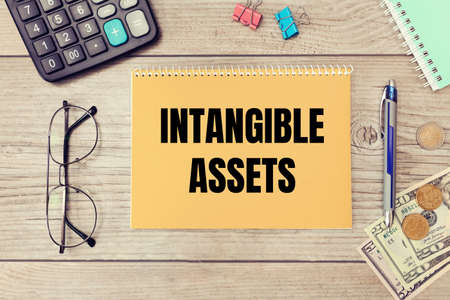 Intangible assets is written on a notepad on an office desk with office accessories.の写真素材