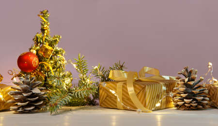 Christmas or new year composition, wooden pink background and golden christmas decorations and giftsの写真素材