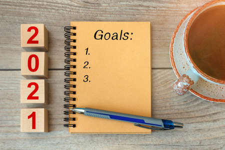 2021 GOALS - inscription on a notebook and wooden cubes, a cup with coffee.