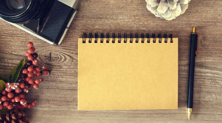 Notepad with pen and retro photo camera on wooden surfaceの写真素材