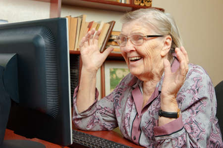 An elderly woman is studying the computer and watching the internetの写真素材