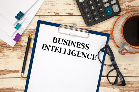 BUSINESS INTELLIGENCE is written in a document on the office desk with office accessories.の写真素材