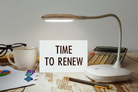 Office desk with a lamp that illuminates the inscription Time to RENEWの写真素材