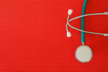 Stethoscope on a red top view with free space