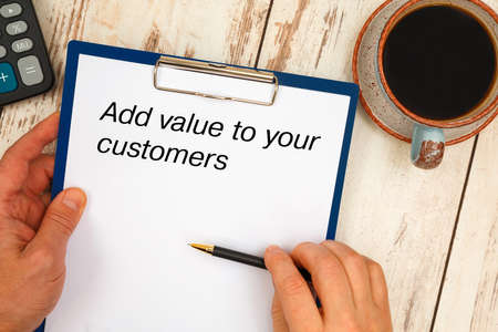 Paper with text Add value to your customers on the office table, calculator and cup of coffee