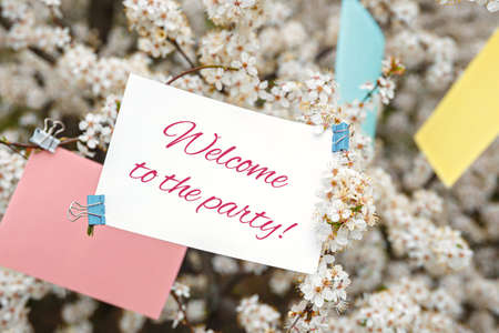 White card with the inscription Welcom To The Party on a background of white flowers of cherryの写真素材