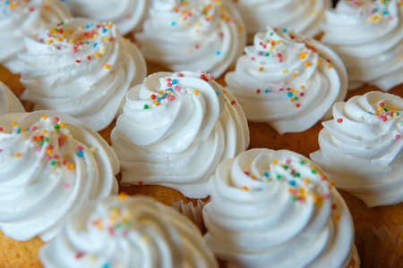 Gourmet Cupcakes with White Creamy and Colored Sprinklesの写真素材