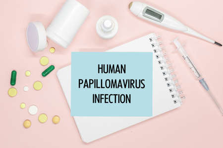 Notebook page with text Human papillomavirus infection on a table with pills and syringe. Medical concept.の写真素材