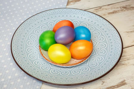 Colorful bright Easter holiday eggs on a plate with an ornament
