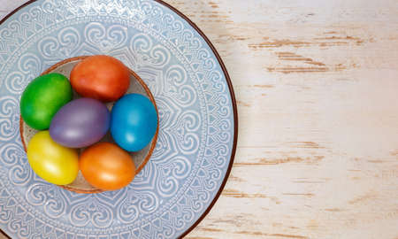 Colorful bright Easter holiday eggs on a plate with an ornamentの写真素材