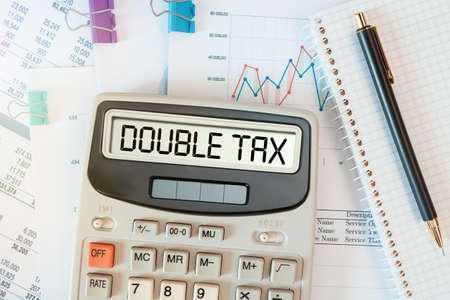 DOUBLE TAX words on calculator. Business and tax concept. Time to pay tax in year.の写真素材