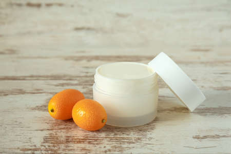 A white jar with cosmetic cream and Kumquat fruit on a wooden background.の写真素材