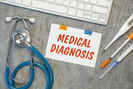 Paper with MEDICAL DIAGNOSIS on the office desk, stethoscope and keyboard, top viewの写真素材