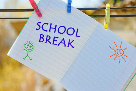 School notebook with the inscription - School Break, hanging on clothespins.