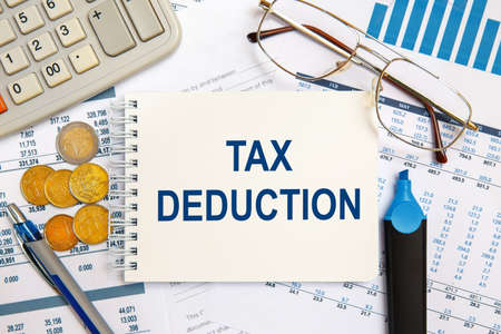 Notebook with the text TAX DEDUCTION on the office table among the stationery.の写真素材