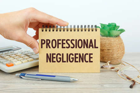 PROFESSIONAL NEGLIGENCE is written on a notepad on an office desk with office accessories.の写真素材