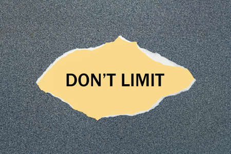 DON'T LIMIT - written on torn yellow paper. Gray backgroundの写真素材