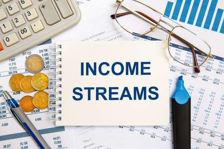 Income Streams is written in a notebook on an office table with office supplies.の写真素材