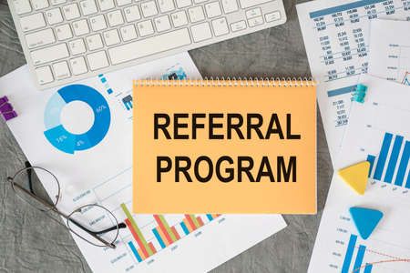 Referral program is written in a document on the office desk with office accessories.の写真素材