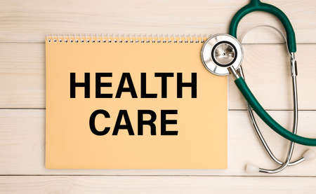 Notepad with the inscription HEALTH CARE and stethoscope. Medical concept.の写真素材