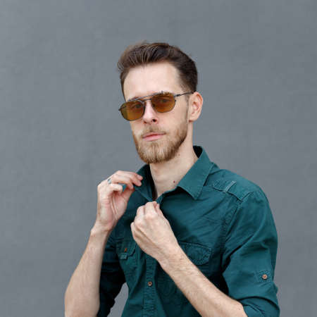 Portrait of a young man in sunglasses on a gray backgroundの写真素材