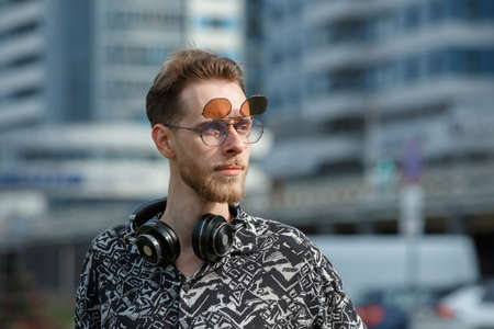 Portrait of a young man in sunglasses and headphones against the background of a modern cityの写真素材