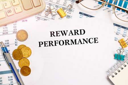 Desktop office desk, notebook, glasses, pen and documents with inscription REWARD PERFORMANCEの写真素材