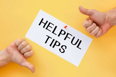 Male hands show signs of approval or disapproval. Postcard with the inscription Helpful Tips on a yellow backgroundの写真素材