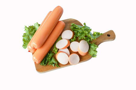 Sausages with lettuce leaves on a wooden board. Top view isolate on a white background.の写真素材