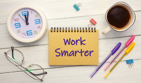 Work Smarter - an inscription on a notebook on a table with a clock and office supplies. Business conceptの写真素材