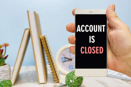 Smartphone in hand with the inscription - Accaunt is closed next to office suppliesの写真素材