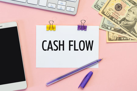 Paper with the inscription CASH FLOW, keyboard, phone and money.の写真素材
