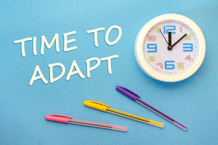 Time To Adapt - lettering on a blue background, clock and pensの写真素材