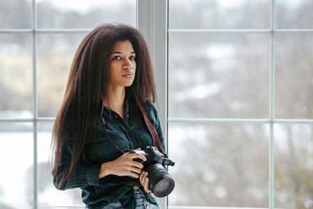 A beautiful African-American photographer girl with a camera. Photo shoot in the studio.の写真素材