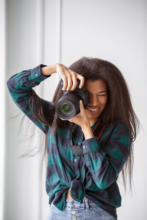 A beautiful African-American photographer girl with a camera. Photo shoot in the studio.の写真素材