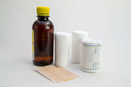 Bandages, patch and a bottle of disinfectant on white background. These are the most important tools for treating a woundの写真素材