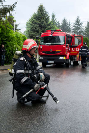 A firefighter ready for action with a red firetruck in background. Romanian national emergency drill.のeditorial素材