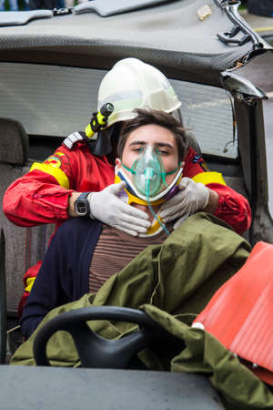 Firefighter helping wounded young man in car accident - Romanian National Emergency Exerciseのeditorial素材