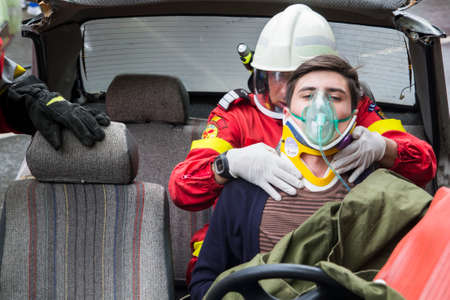 Firefighter helping wounded young man in car accident - Romanian National Emergency Exerciseのeditorial素材