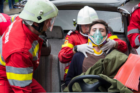 Firefighters helping wounded young man in car accident - Romanian National Emergency Exerciseのeditorial素材