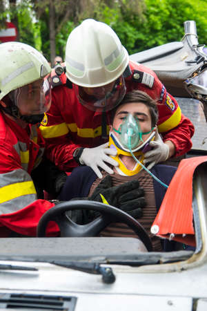 Firefighters helping wounded young man in car accident - Romanian National Emergency Exerciseのeditorial素材