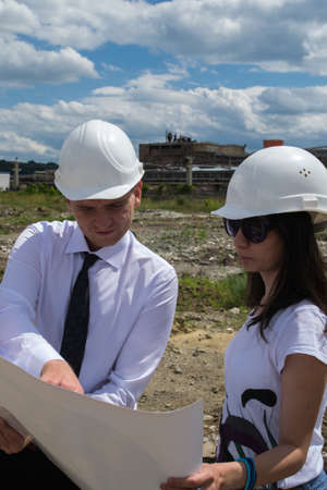 Young men engineer and young women engineer analising blueprints on site.の写真素材