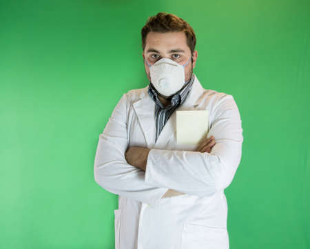 Young male doctor with mask on his face and blank envelope in his pocketの写真素材