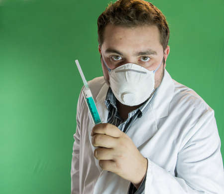 Young doctor with mask holding a syringeの写真素材
